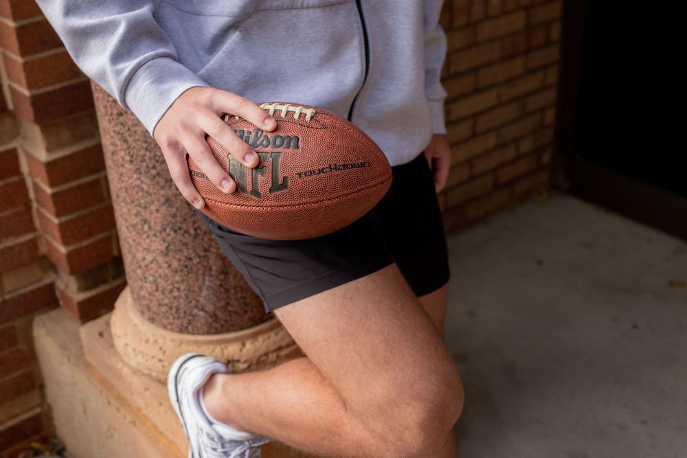 A Wilson basketball is held in someone's hands showing the leather texture and grip of the ball.
