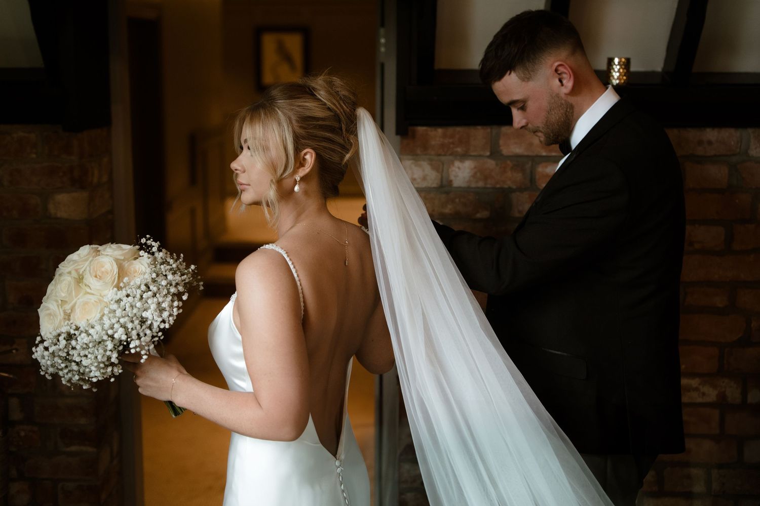 Wedding couple embracing in a rustic indoor venue with romantic lighting.