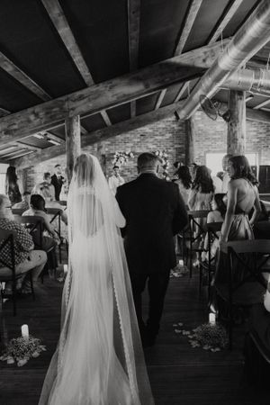 Wedding ceremony in a rustic brick venue with exposed wooden beams and gathered guests.
