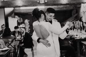 Couple sharing their first dance at a rustic indoor wedding reception.
