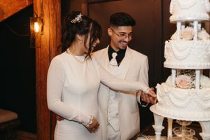 Newlyweds cutting their elegant white wedding cake together.