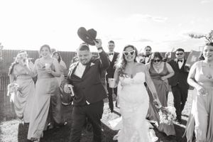 Black and white photo of wedding party walking outdoors with joyful expressions.