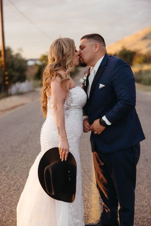 Romantic sunset portrait of newlyweds sharing an intimate moment on a country road.