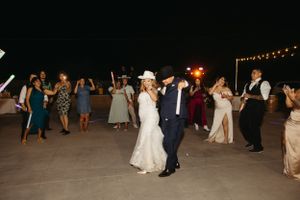 Wedding reception dancing under string lights at an outdoor venue at night.