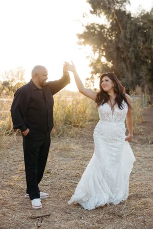 A couple celebrates with a high five in an outdoor setting during their wedding photoshoot.