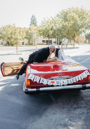 A red vintage convertible with 'Just Married' banner displayed in a parking lot.