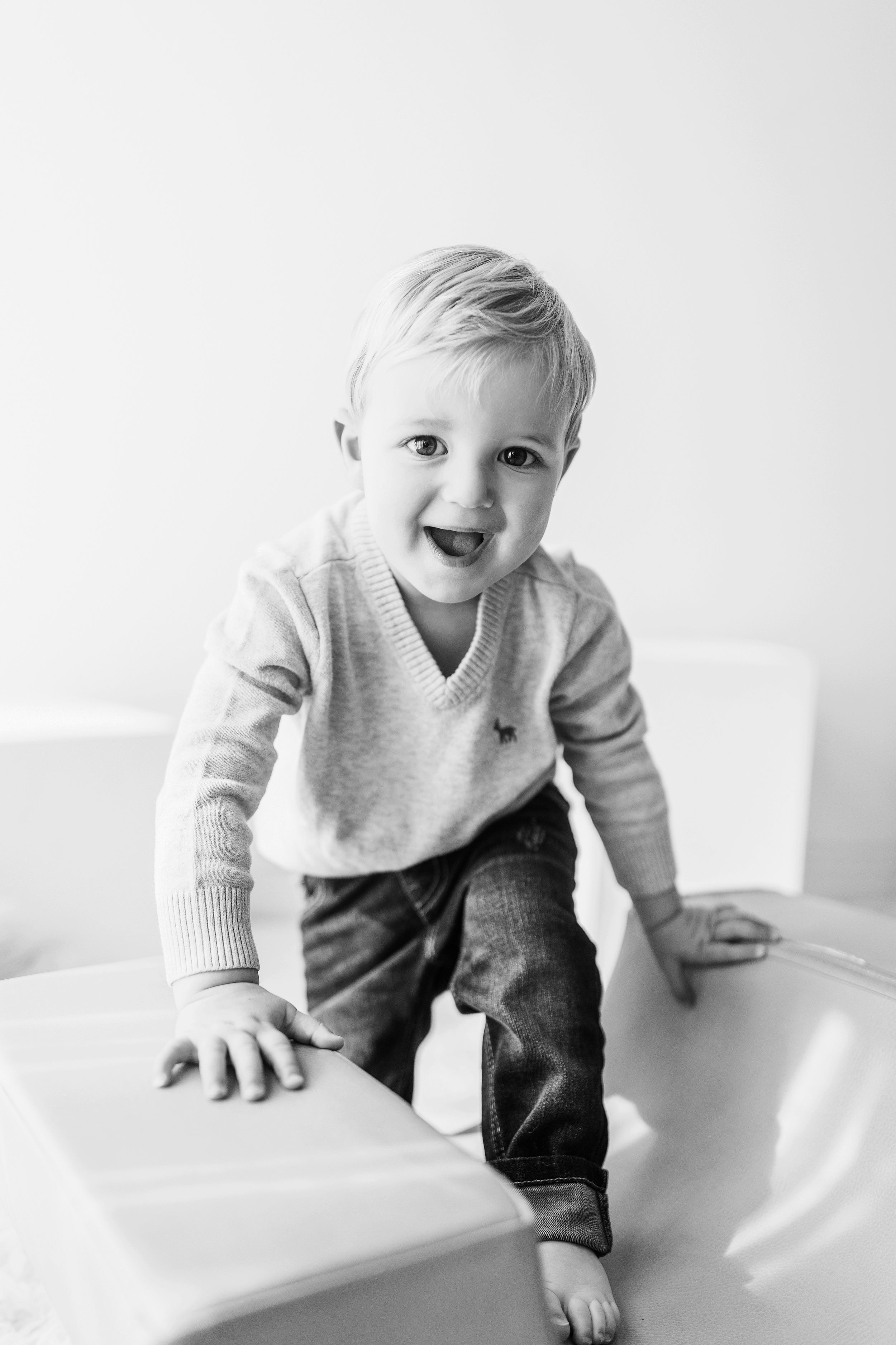 A sequence of black and white photos showing a baby crawling and playing on a white surface with joyful expressions.