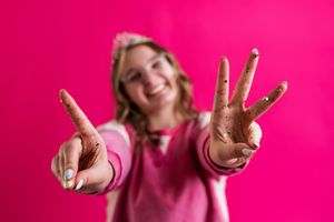 Person in pink background showing peace signs and playful expressions in a series of dynamic poses.