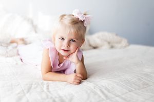 A soft and dreamy lifestyle photo of someone resting on white bedding with pink bow accessories.
