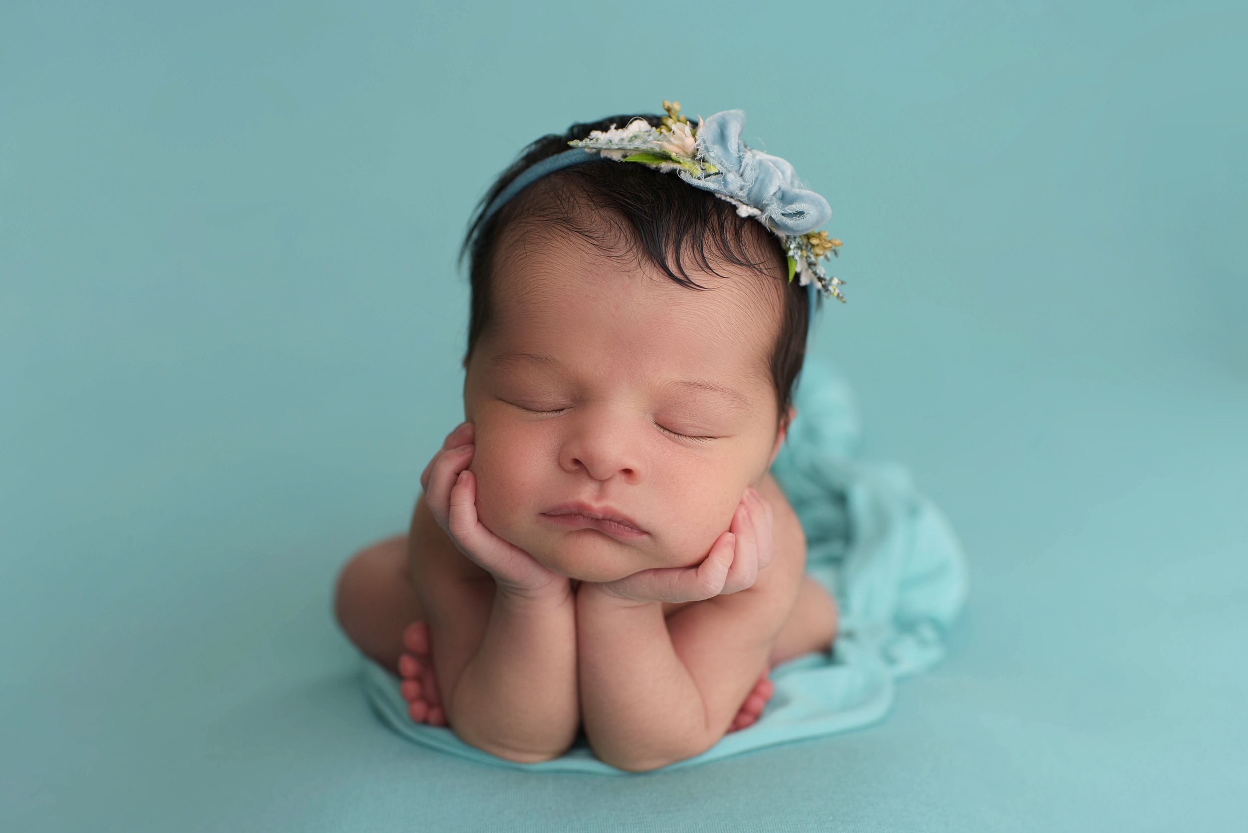 Baby girl sleeping in the froggy pose on an aqua colored blanket in Colorado Springs