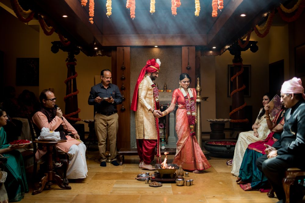 Traditional Indian wedding ceremony with bride and groom standing together in traditional attire as guests look on.