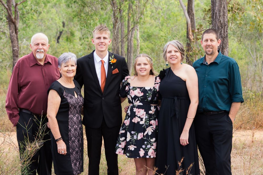 Extended family members posed together for formal portrait in rustic outdoor setting.