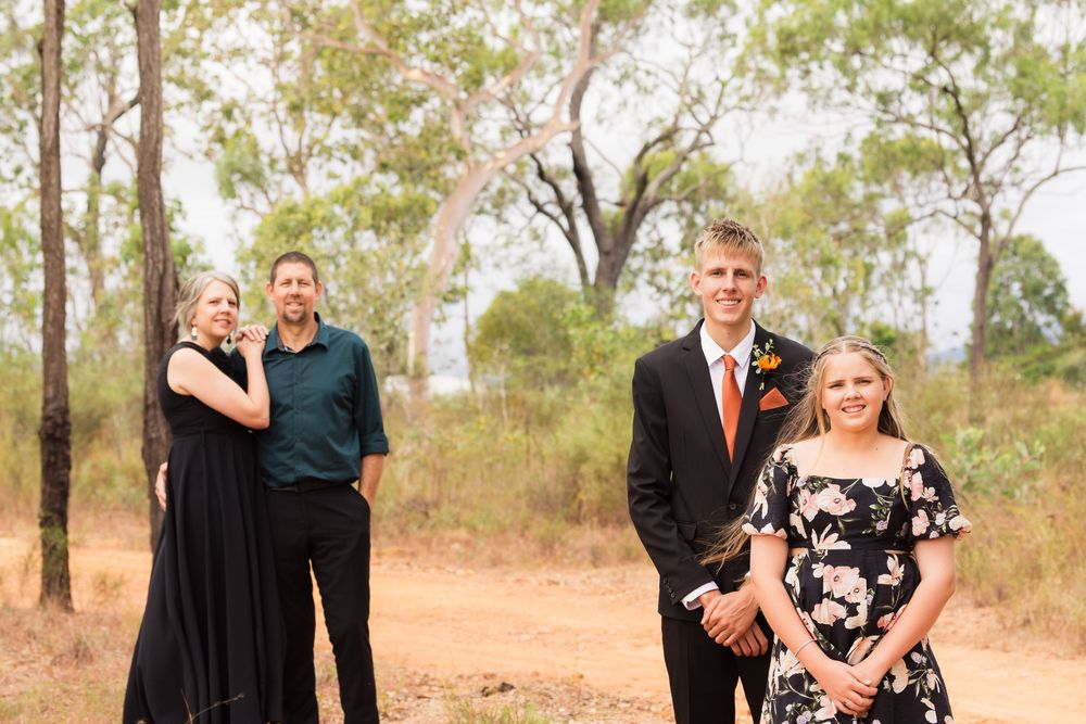 Family members arranged in formal grouping against backdrop of outback bushland.