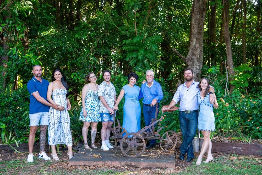 Extended family gathering for casual outdoor photos in a lush green woodland setting.