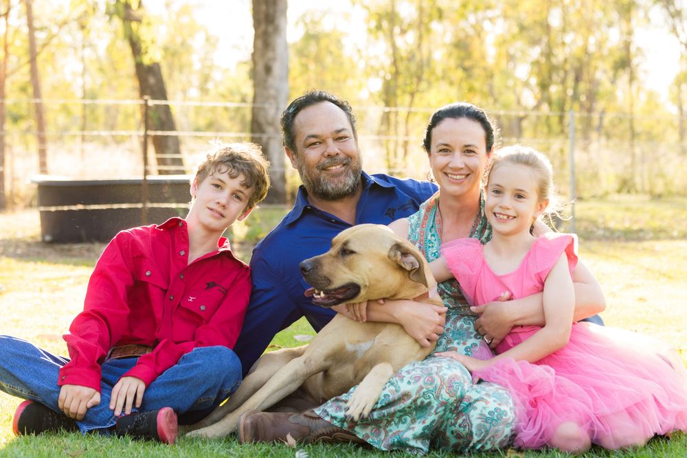 A group sits together outdoors while enjoying a family photo session in golden autumn sunlight.