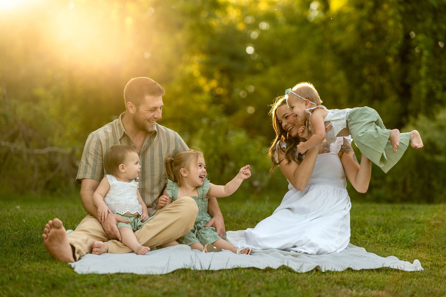 A group poses together in a sunlit meadow wearing coordinated pastel outfits during golden hour.