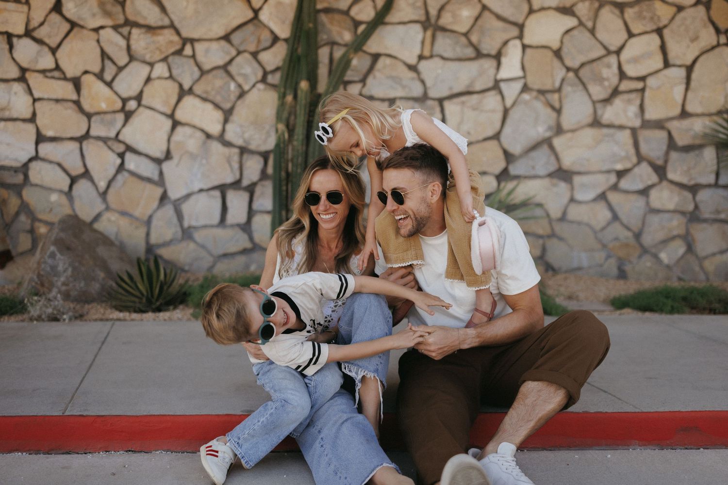 Happy family sharing laughter and joyful moments together outdoors with mountains in the background at sunset.