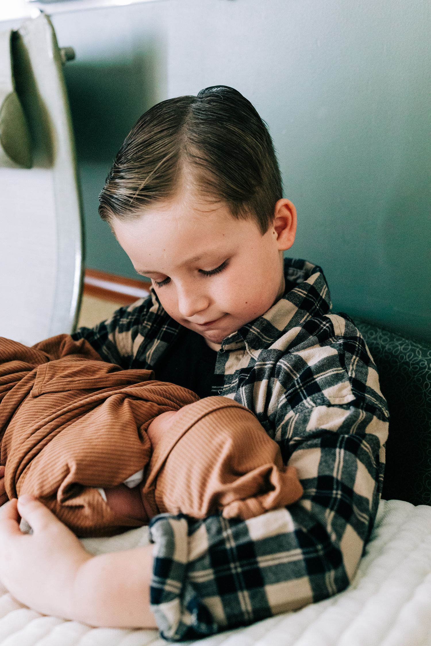 Big brother holding little brother swaddled in brown, Santa Maria, CA
