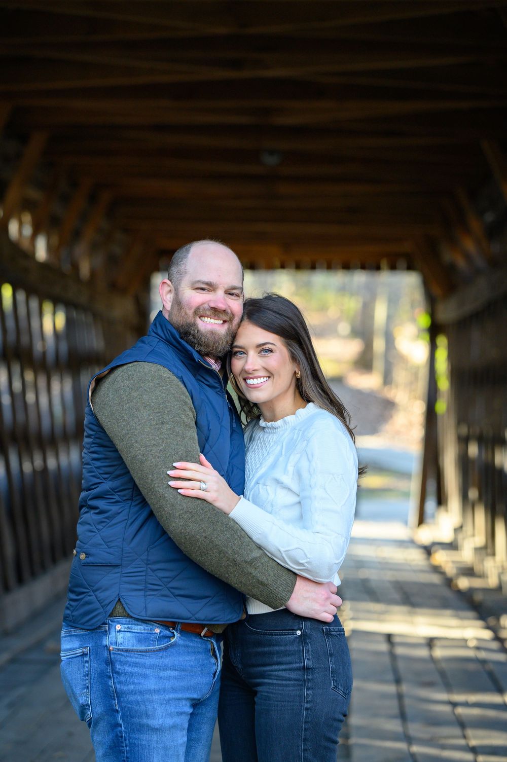 A couple embraces and shares joyful moments together in a rustic wooden covered bridge setting.