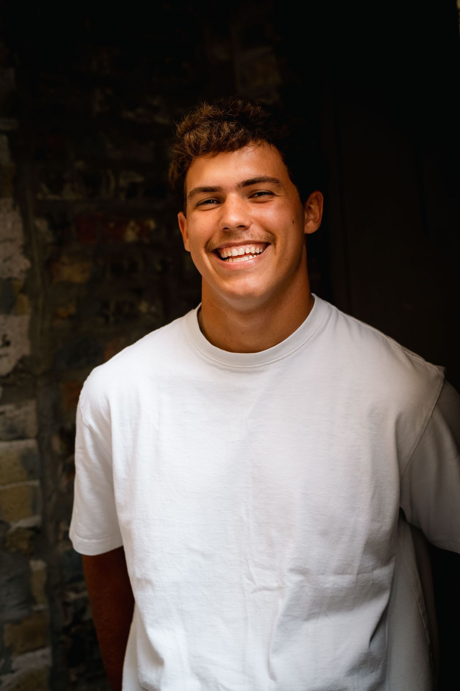 A series of headshots showing someone in a white t-shirt smiling against a dark background.