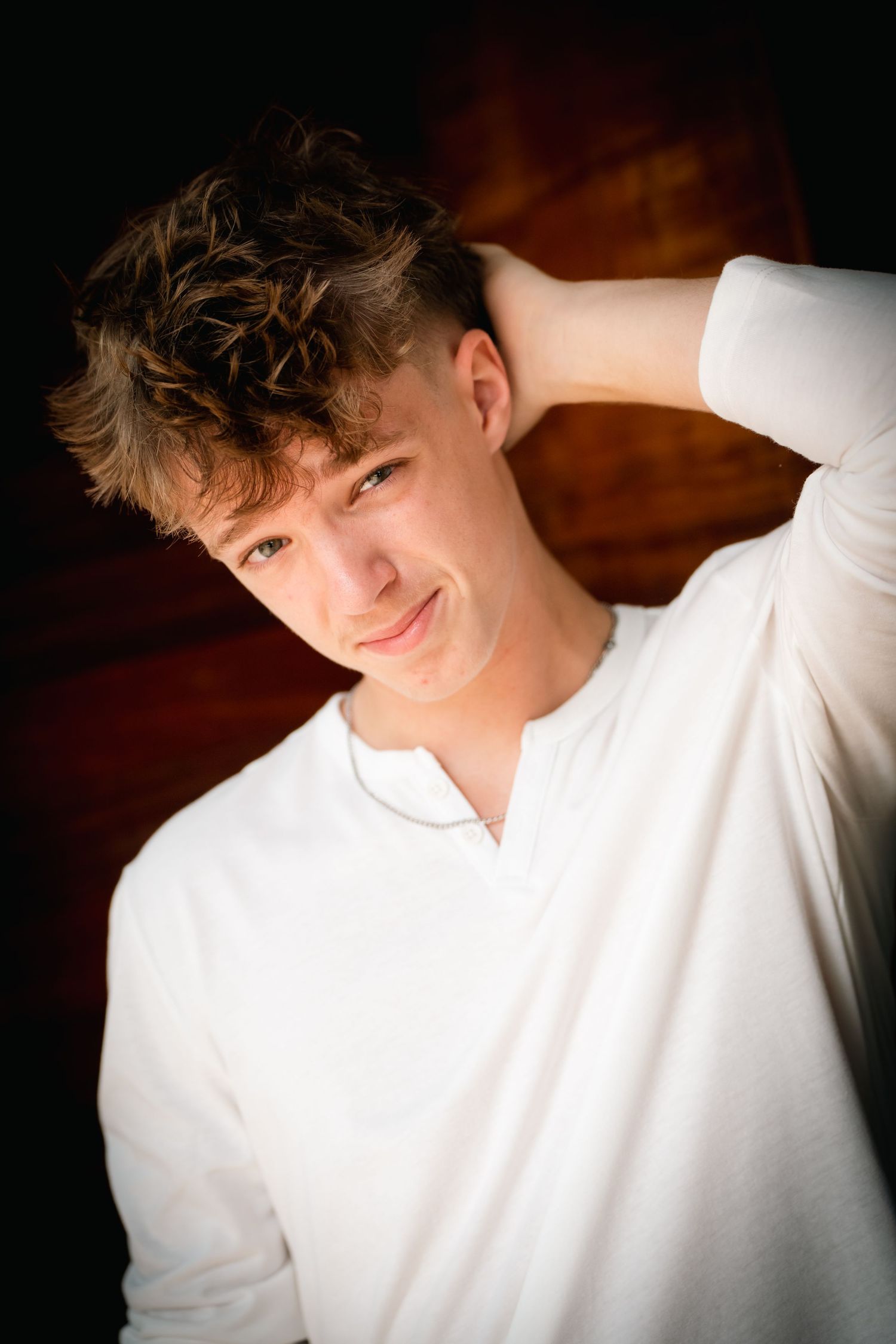 Portrait series in moody lighting shows person in white sweater against dark background with varying poses and expressions.