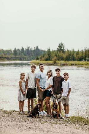 A group poses together on a sandy beach with trees in the background at sunset.