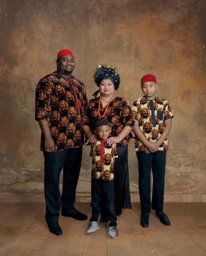Four people wearing colorful African-inspired patterned shirts pose for a formal portrait against a textured backdrop.