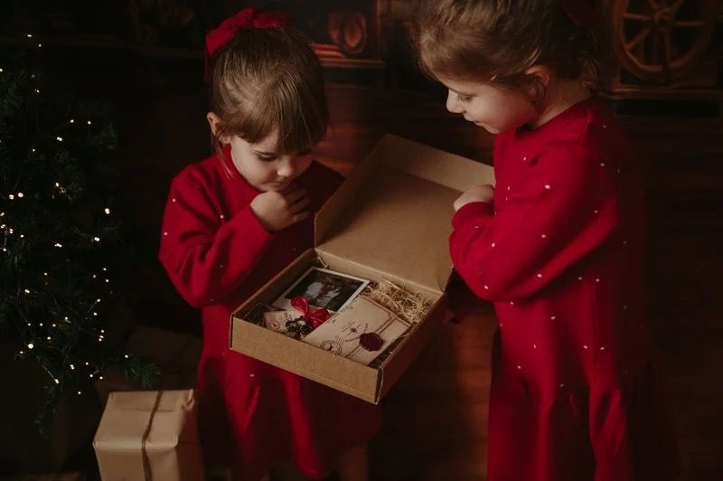Two children discovering a wooden toy box during a previous Christmas photography session.