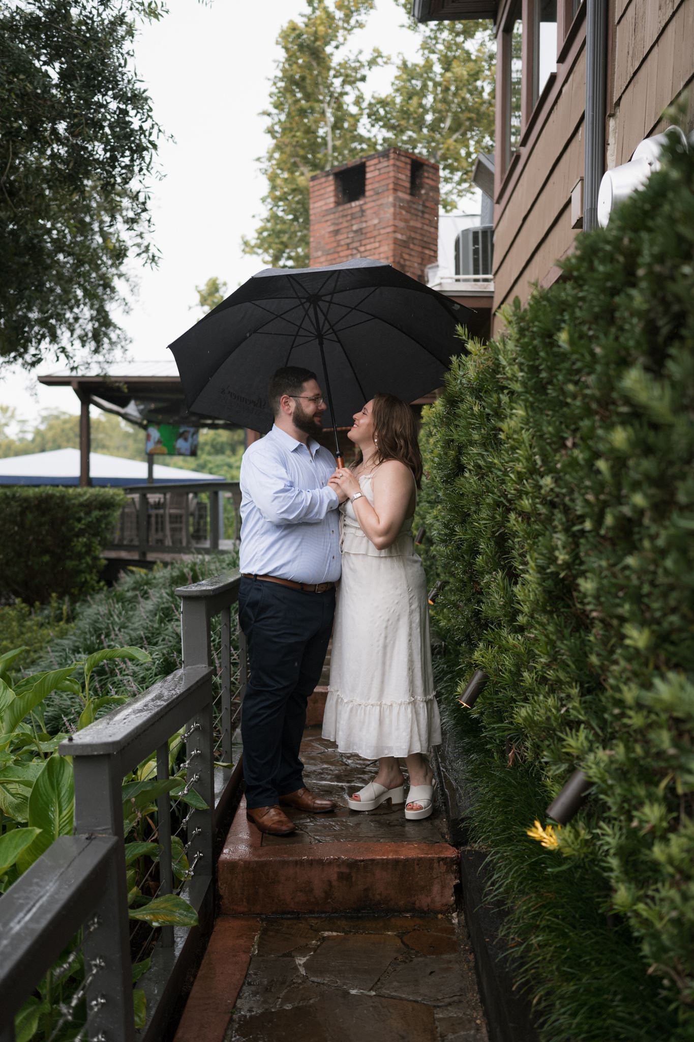 Newly engaged couple embracing beneath the umbrella after their proposal