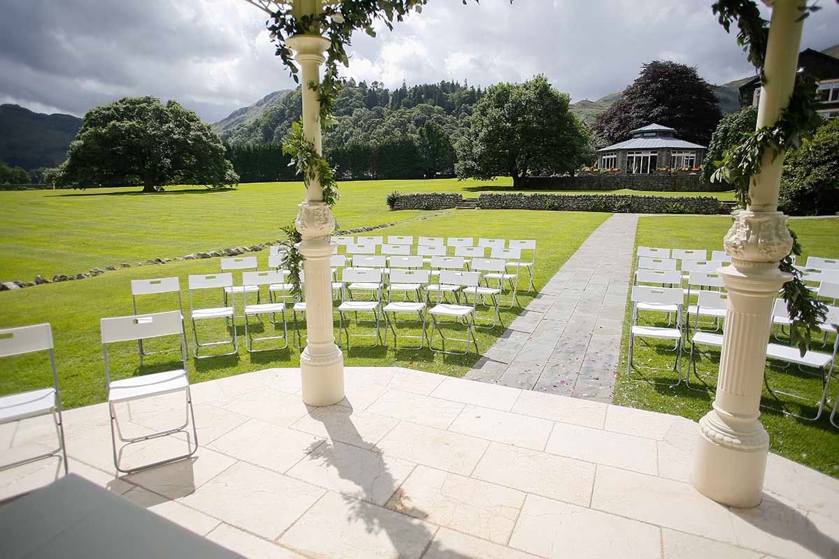 Outdoor wedding ceremony setting with white chairs and a garden aisle viewed from the gazebo at Inn on the Lake.