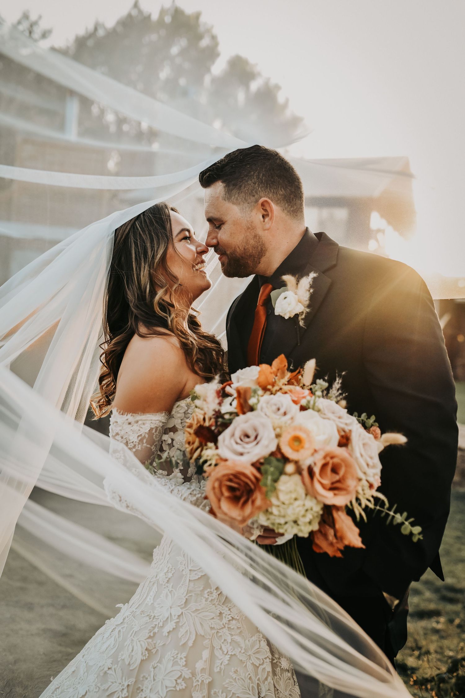 the sunsets behind a newly married bride and groom as her veil flows in the wind at lucky spur ranh