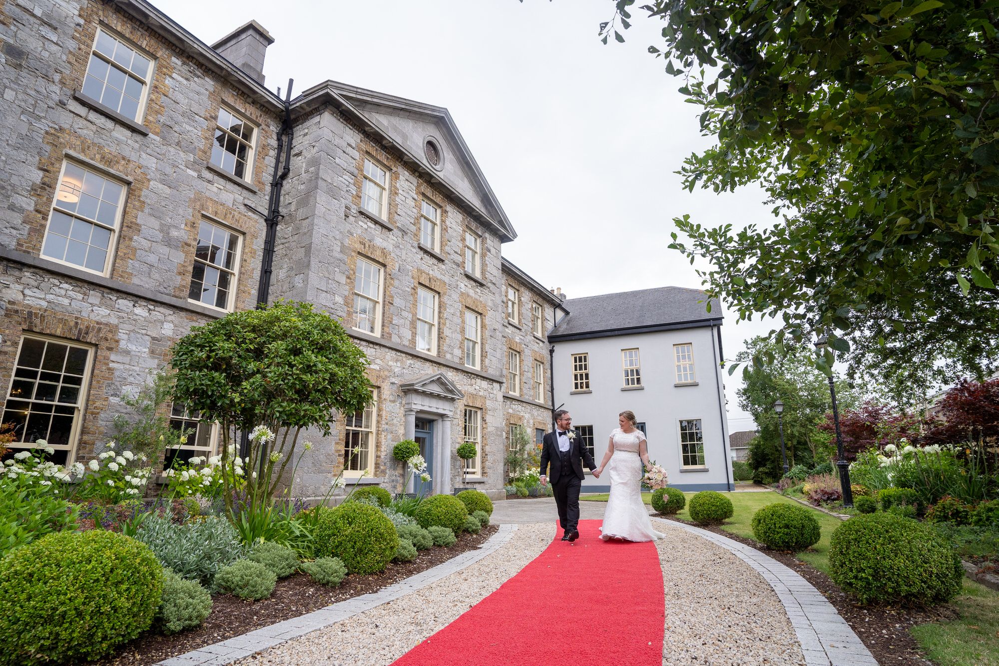 Bride and groom walking on red carpet tat elegant and historic Abbey in Athy, County Kildare photo by Anthony Kane - AK Wedding photography