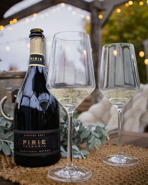 Pirie Tasmania sparkling wine bottle with two elegant glasses on burlap.