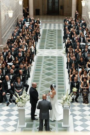 Bride and groom exchange vows at altar in stunning historic building with large seated wedding crowd.