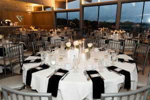 Elegant black and white wedding reception tables with candles, floral centerpieces, and floor-to-ceiling windows.