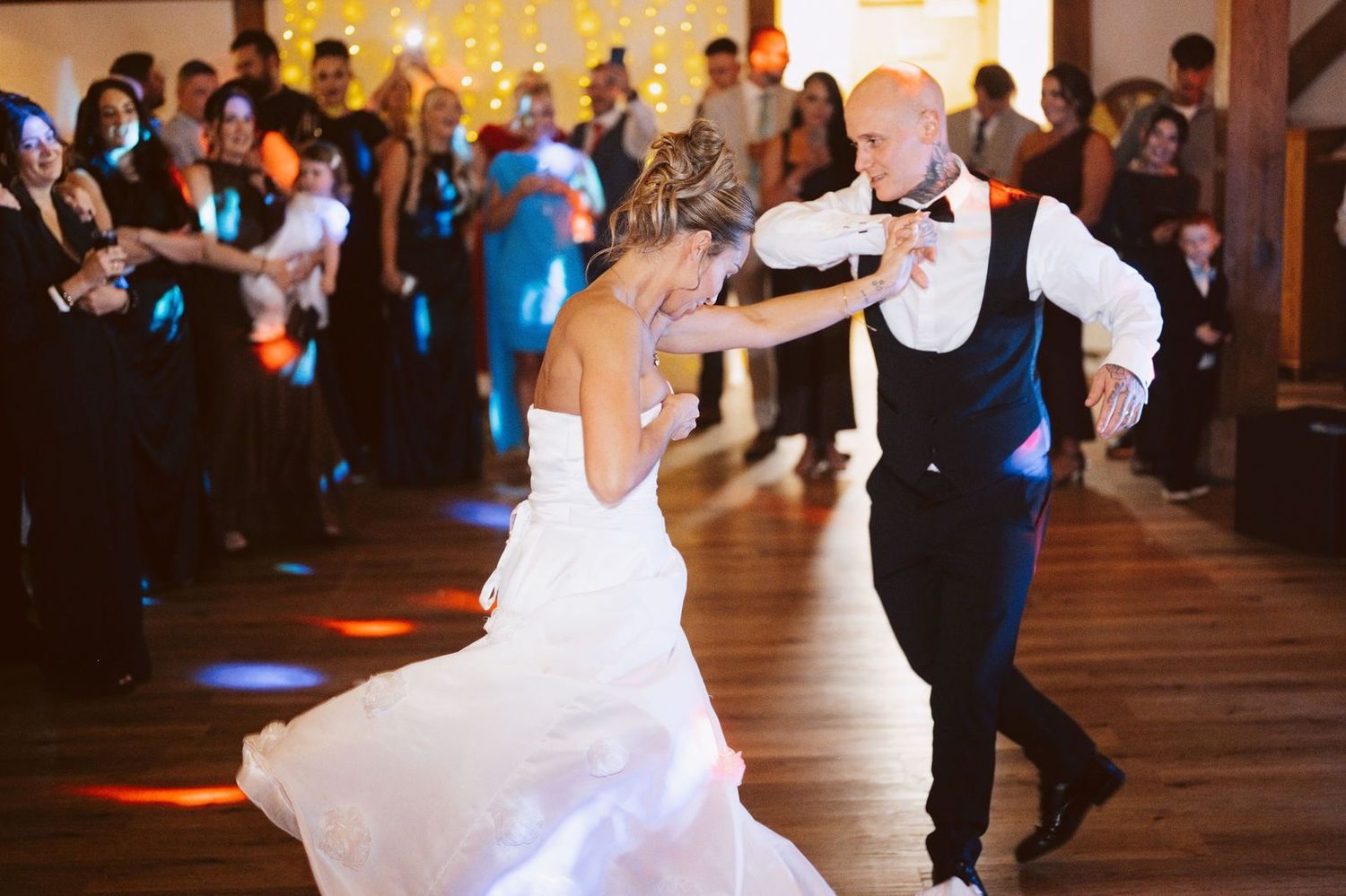 Bride and groom's first dance on a wooden floor as guests watch and film, Sandhole Oak Barn wedding