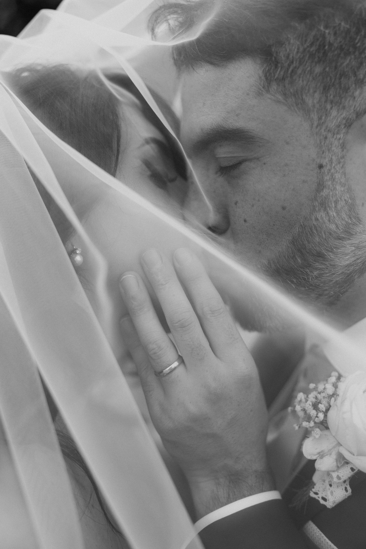 I volti di Marco ed Elena vicini sotto il velo, in bianco e nero.