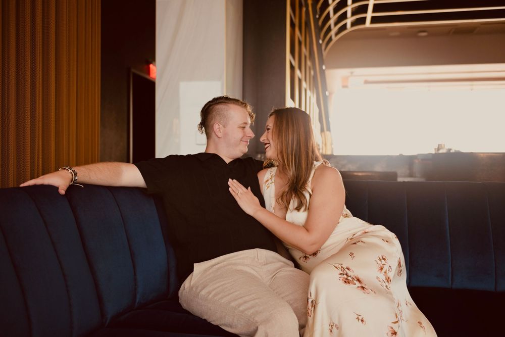 Couple sharing a romantic moment on a blue velvet sofa in a stylish bar lounge.