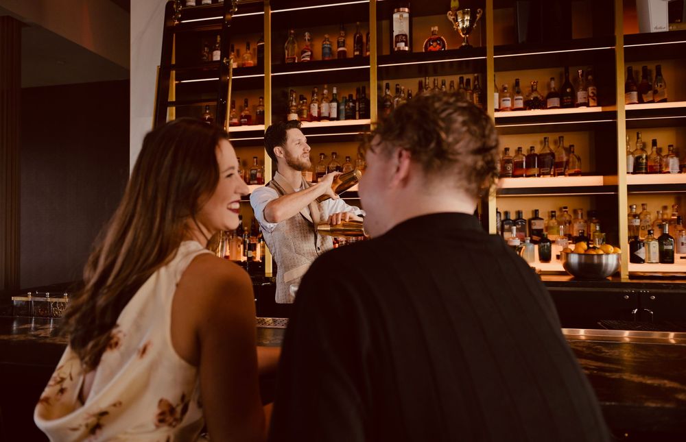 Couple enjoying drinks at an upscale bar with a bartender serving cocktails.