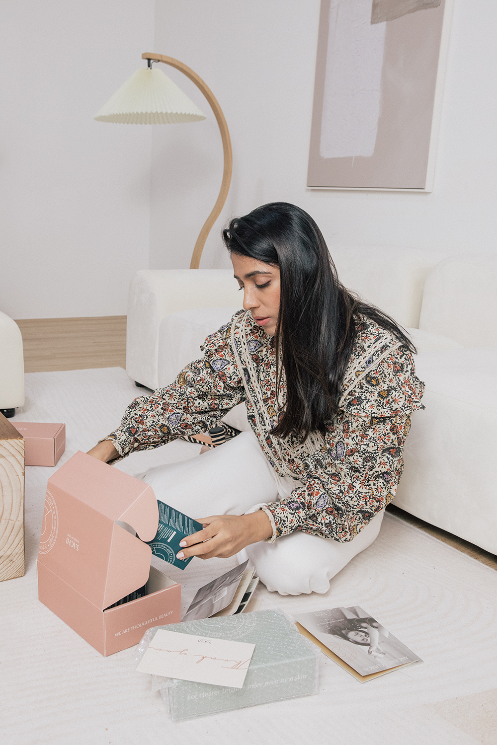 Person in floral print dress unboxing items on a white table.