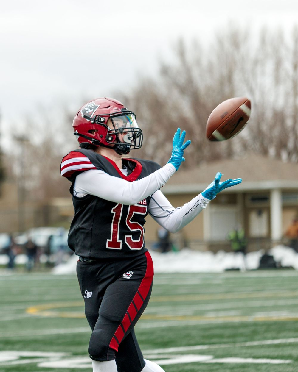 Regina Riot player #15 catches a pass wearing blue gloves in a football game.