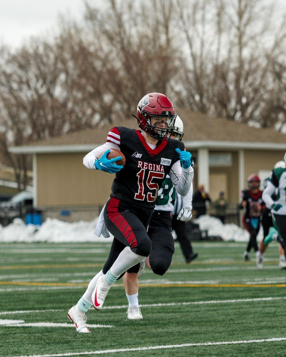 Regina Riot player #15 runs with the ball during a football game.