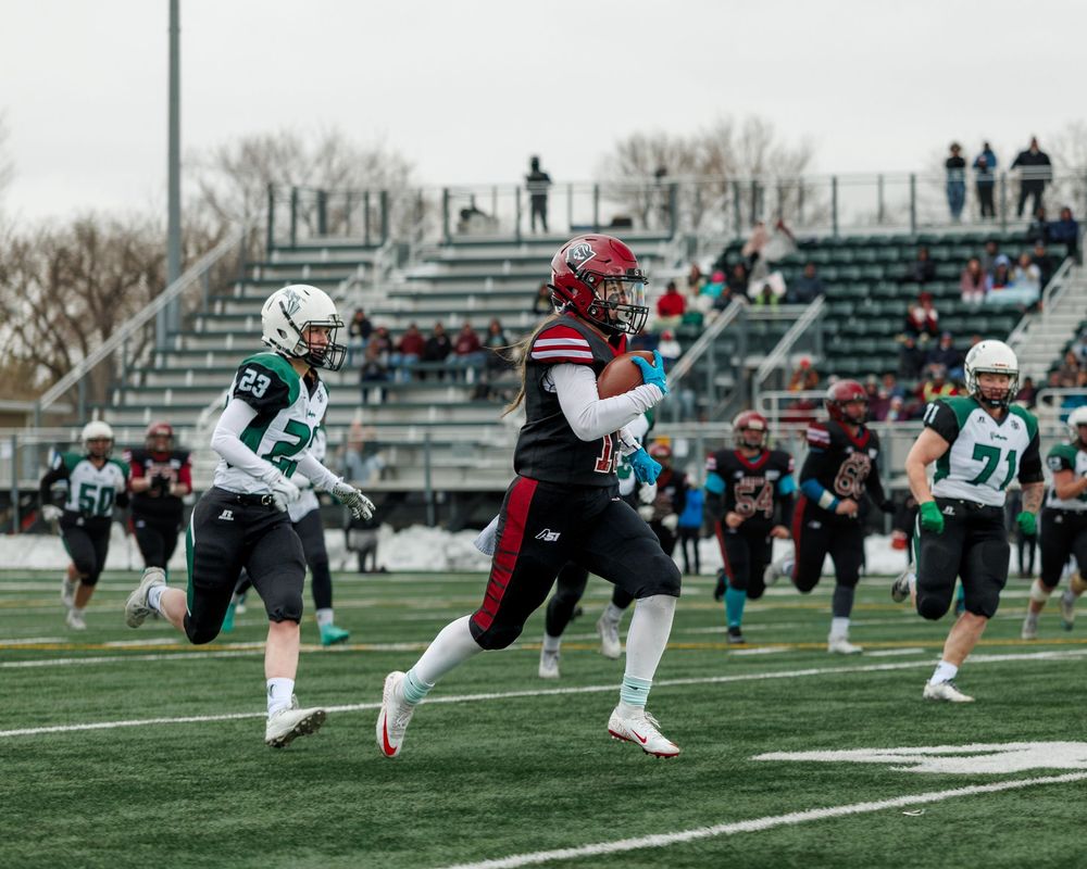 Regina Riot player runs past defenders during a women's football game.