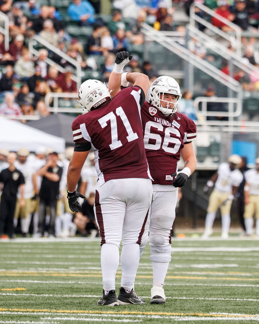 Thunder offensive linemen numbers 71 and 66 celebrate together on the football field during a game.