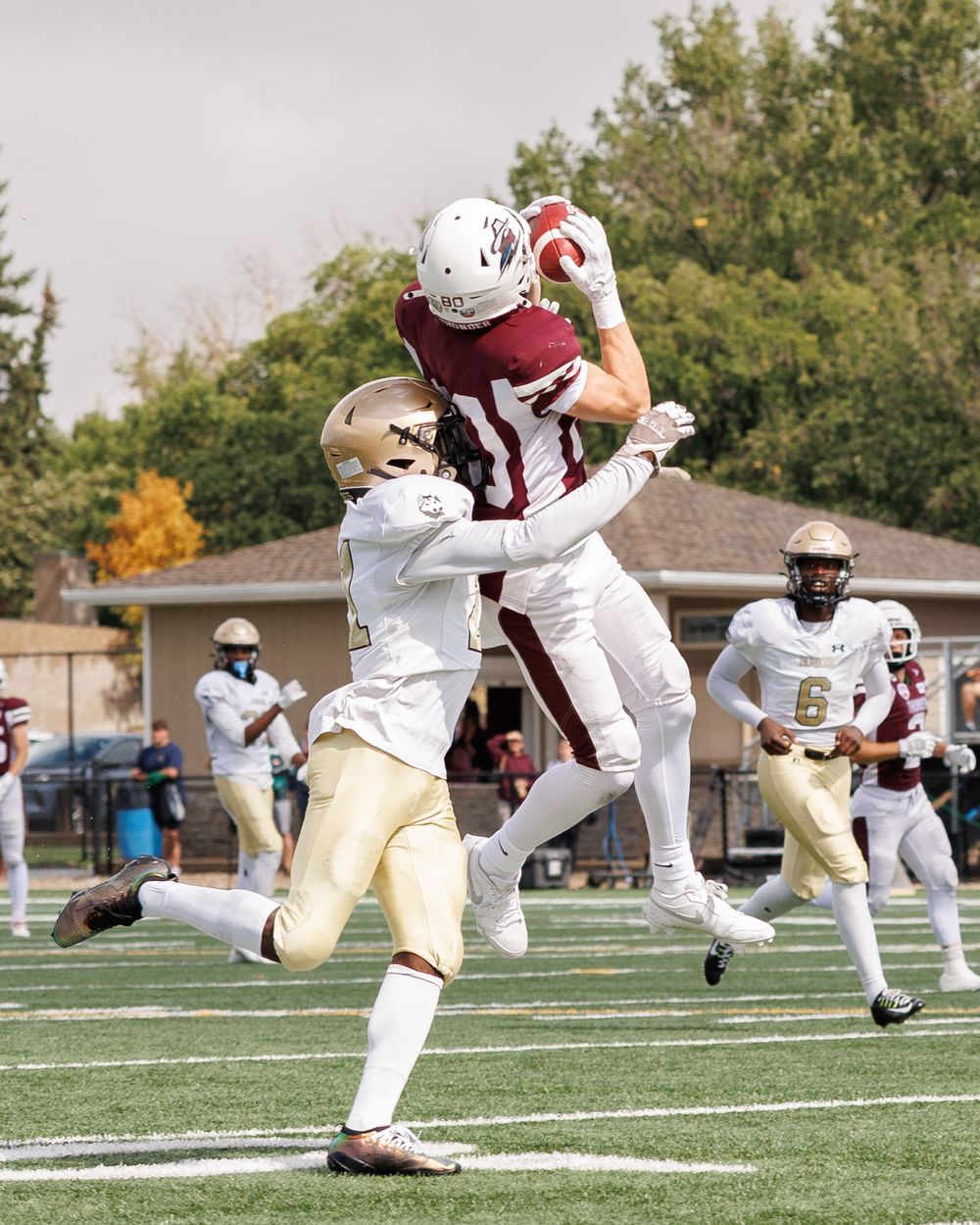 Thunder football player leaps to make an impressive catch over defenders during a college football game.