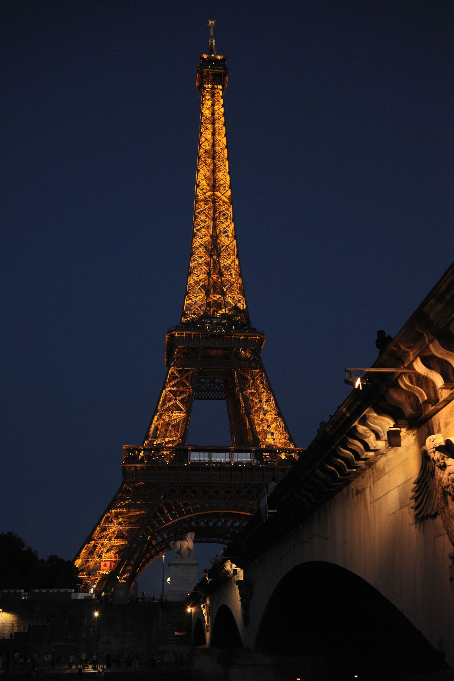 Notre-Dame Cathedral twin towers rise above Seine river stone steps at dusk, Paris, France.
