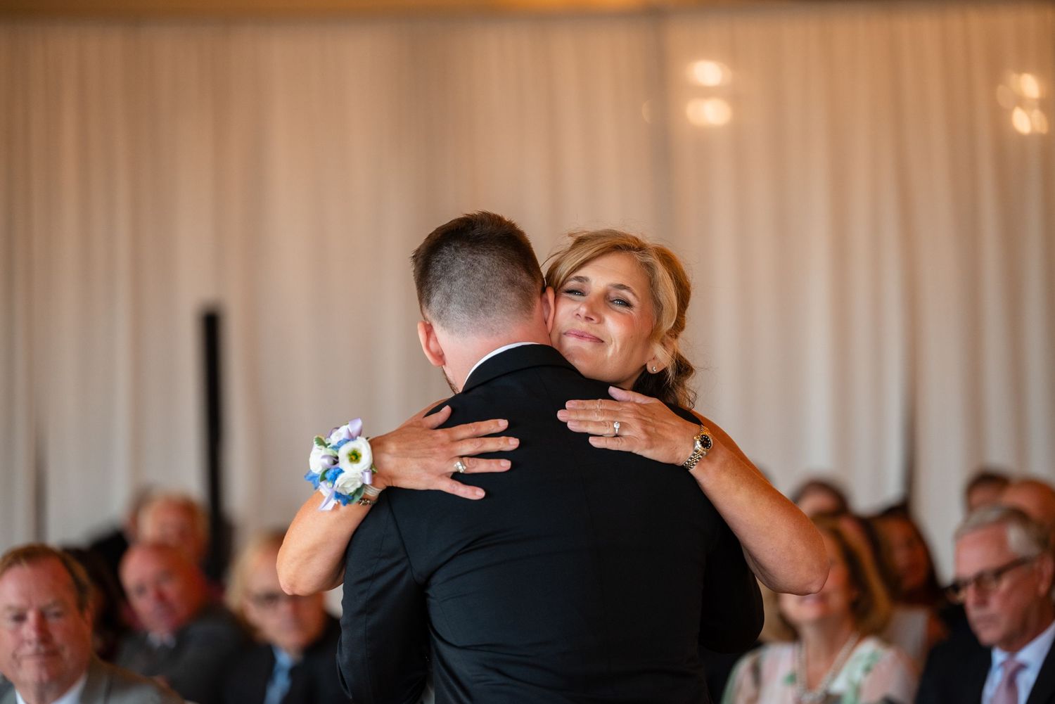 Mother and groom share an emotional hug during wedding reception mother-son dance at elegant venue.