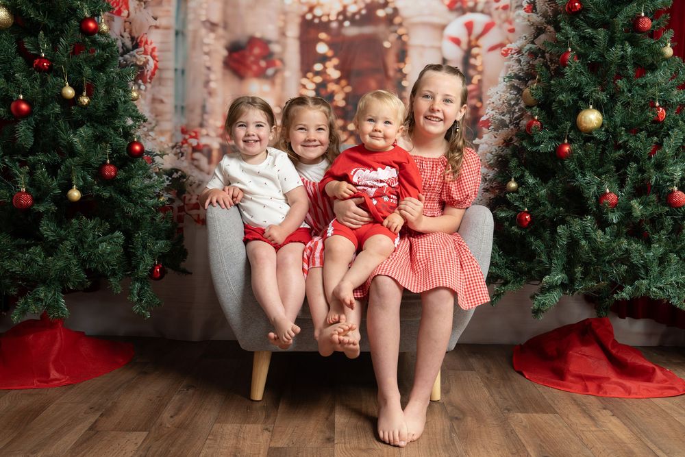 four siblings in front of a christmas backdrop