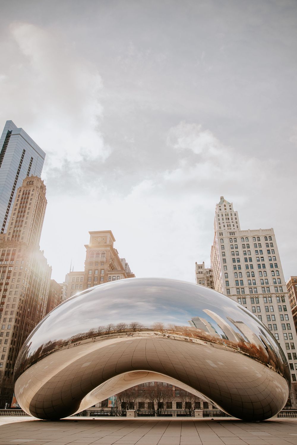 Cloud Gate sculpture reflecting Chicago skyline in Millennium Park on a cloudy day.
