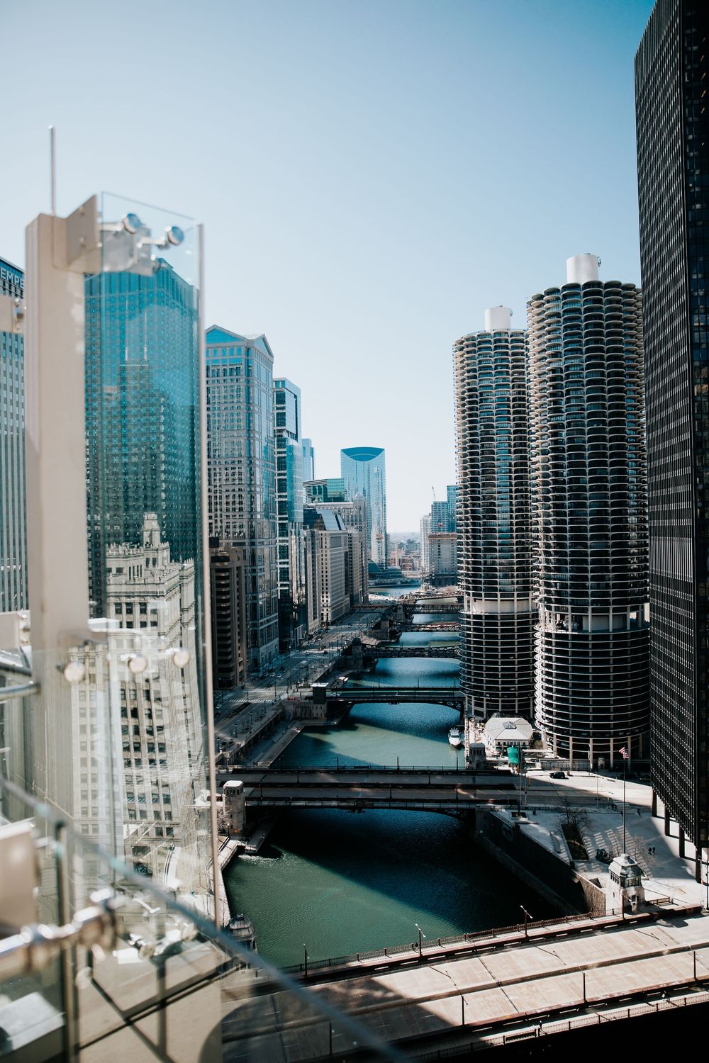 Aerial view of Chicago River with skyscrapers and Marina City towers lining the waterway on a clear sunny day.